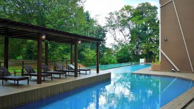 a swimming pool with tables and chairs next to a building at Hotel Grand Baron in Tupai
