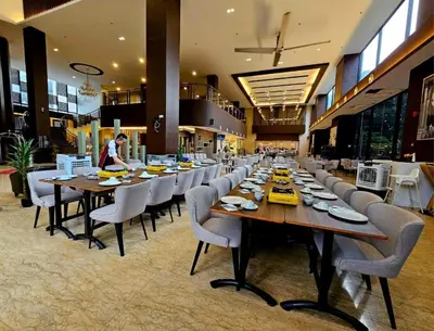 a dining room with long tables and chairs in a restaurant at Hotel Grand Baron in Tupai