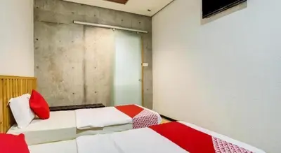 two beds in a room with red and white at OYO 89454 Hotel Pavilion Inn in Ayer Tawar
