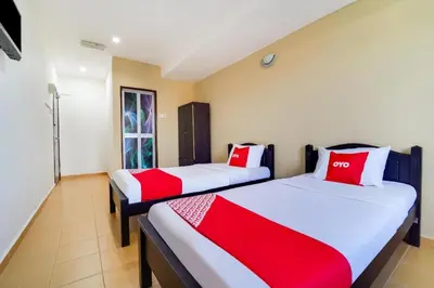 two beds in a room with red and white pillows at OYO 44058 MOTEL SRE BAYAM in Kampong Ayer Hitam