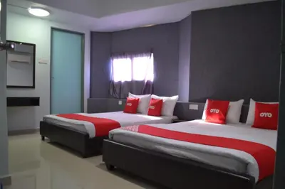two beds in a hotel room with red pillows at OYO 89737 Hotel Tishoa in Kampong Batu Tiga