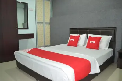 a bedroom with a large bed with red pillows at OYO 89737 Hotel Tishoa in Kampong Batu Tiga
