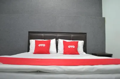 a bed with two red pillows on it at OYO 89737 Hotel Tishoa in Kampong Batu Tiga