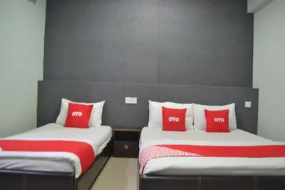 two beds with red pillows in a room at OYO 89737 Hotel Tishoa in Kampong Batu Tiga