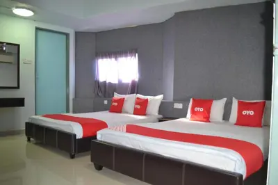 two beds in a room with red and white pillows at OYO 89737 Hotel Tishoa in Kampong Batu Tiga