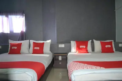 two beds with red and white pillows in a room at OYO 89737 Hotel Tishoa in Kampong Batu Tiga