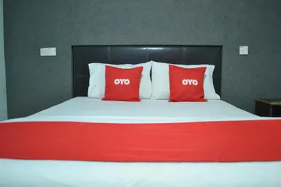 a large bed with two red pillows on it at OYO 89737 Hotel Tishoa in Kampong Batu Tiga