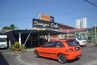 an orange car parked in front of a sandwich cafe at SPOT ON 89821 Batu Maung Sempoi Inn and Cafe in Kampong Batu Maung
