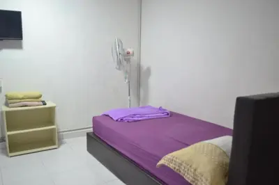 a small room with a bed with purple sheets at SPOT ON 89821 Batu Maung Sempoi Inn and Cafe in Kampong Batu Maung