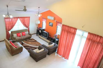 a living room with a couch and chairs and a television at Hotel O D'hitech Home in Kampong Sungai Badak