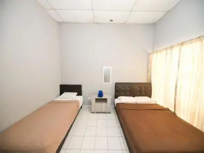 a room with two beds and a table in it at Hotel O Iman Roomstay Gua Musang in Kampong Keriting
