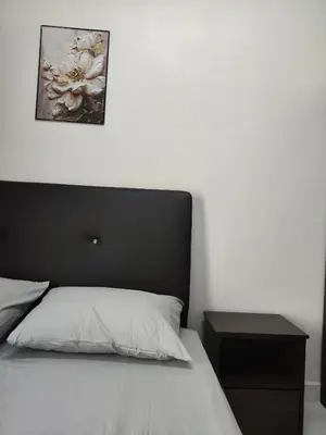 a bedroom with a bed with a black headboard and a table at Imtiyaz Islamic Homestay in Kulim