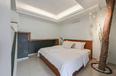 a bedroom with a bed with white sheets and a tree at Cameron Highland Retreat in Tanah Rata