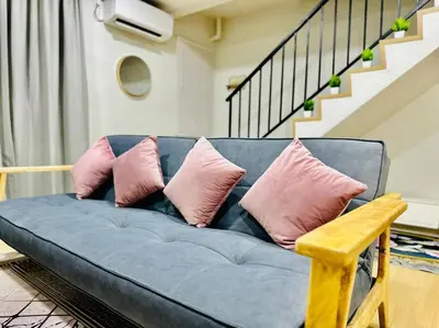 a blue couch with pink pillows in a living room at My Muji Homestay I Massage Chair I Wifi 500 Mbps in Seri Manjung