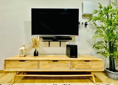 a flat screen tv on top of a wooden entertainment center at My Muji Homestay I Massage Chair I Wifi 500 Mbps in Seri Manjung