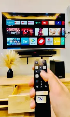 a person holding a remote control in front of a tv at My Muji Homestay I Massage Chair I Wifi 500 Mbps in Seri Manjung