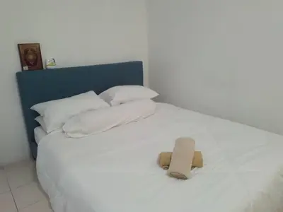 a white bed with white pillows and a brown towel on it at Apartment Cameron Jaya in Tanah Rata