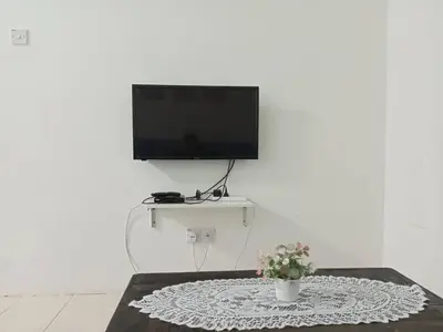 a living room with a tv and a table at Apartment Cameron Jaya in Tanah Rata