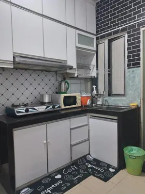 a kitchen with white cabinets and a black and white floor at Apartment Cameron Jaya in Tanah Rata