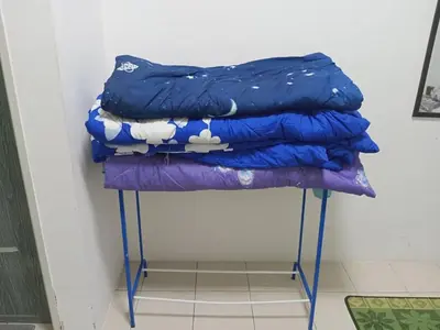 a stack of blankets on a stand in a room at Apartment Cameron Jaya in Tanah Rata