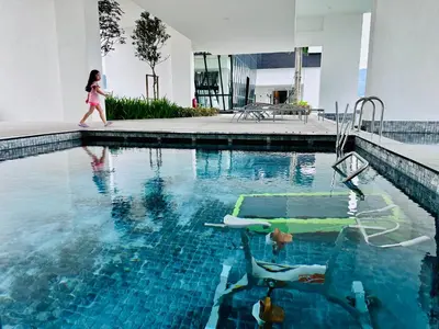 a little girl walking by a swimming pool at Luxury Apartment Sea&City View Georgetown 14 pax in Jelutong