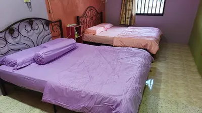 two beds in a room with purple sheets at Homestay Kak Rose Kuala Lipis in Kuala Lipis