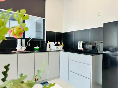 a kitchen with white cabinets and black walls at 12 pax luxury seaview infinity pool apartment in Jelutong