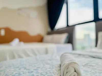 a towel laying on the edge of a bed at 12 pax luxury seaview infinity pool apartment in Jelutong
