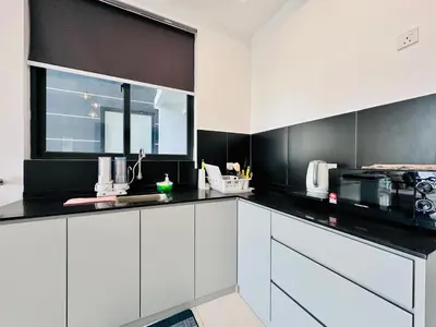 a kitchen with white cabinets and a black wall at 12 pax luxury seaview infinity pool apartment in Jelutong
