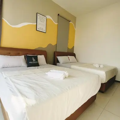 two beds in a hotel room with white sheets at 2 bed room 5 queen bed luxury sea view apartment in Jelutong