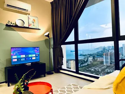 a living room with a large window and a television at 2 bed room 5 queen bed luxury sea view apartment in Jelutong
