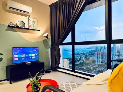 a living room with a large window and a television at 2 bed room 5 queen bed luxury sea view apartment in Jelutong
