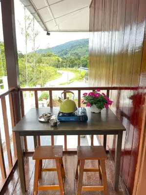 a table with a tea pot on a balcony at Manson Goat Cottage in Cameron Highlands