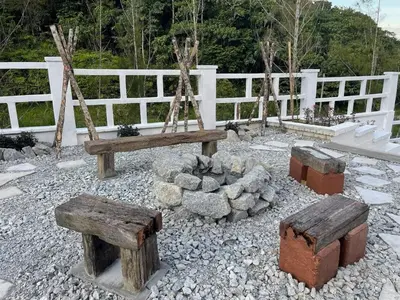 a garden with wooden benches and a fire pit at Manson Goat Cottage in Cameron Highlands