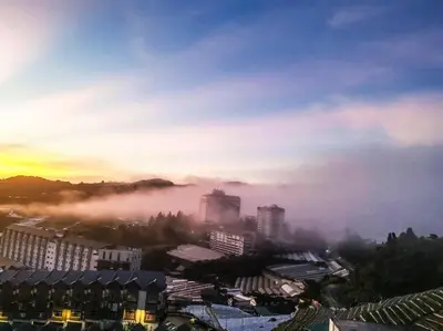 a foggy city with buildings in the distance with the sunset at Sunrise Serenity at Palas Horizon Residence in Brinchang