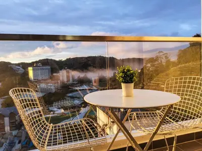 a table and chairs on a balcony with a view at Sunrise Serenity at Palas Horizon Residence in Brinchang