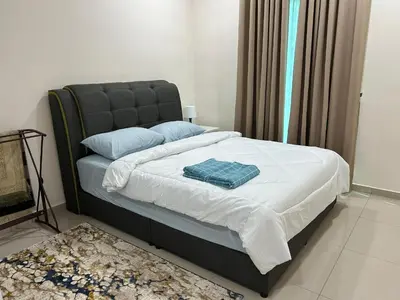 a bedroom with a bed with white sheets and blue pillows at Hazel Luxe Apartment in Permatang Pauh