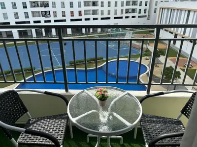 a table and chairs on a balcony with a view of a pool at Hazel Luxe Apartment in Permatang Pauh