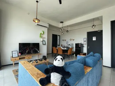 a teddy bear sitting on a blue couch in a living room at 3B2R 2CarPark Tea Time Suite with Infinity Pool in Jelutong