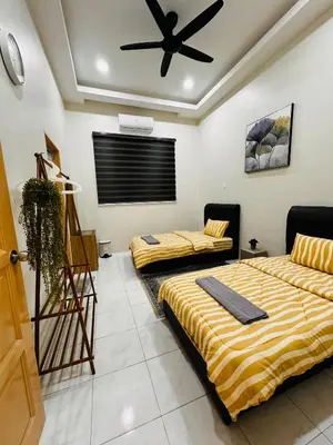 two beds in a room with a ceiling fan at Mia homestay in Teluk Intan