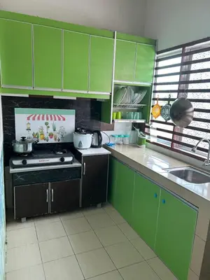 a kitchen with green cabinets and a stove top oven at AMRI KLATE Homestay in Seri Iskandar