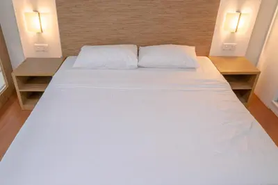 a large white bed in a room with two tables at The CEO Executive Suites in Bayan Lepas