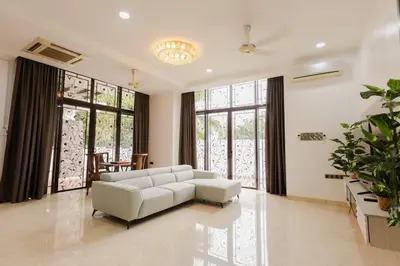 a living room with a white couch and some windows at Gelugor 2Storey Big Bungalow 23pax with BBQ Snooker in Gelugor