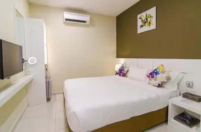 a bedroom with a white bed and a flat screen tv at Hotel Mornington Bukit Permata Lumut in Lumut