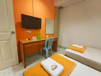 a room with two beds and a desk with a television at Bahagia Stay Georgetown in George Town