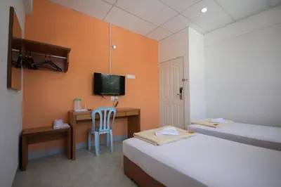 a room with two beds and a desk and a television at Bahagia Stay Georgetown in George Town