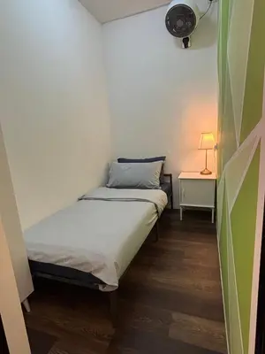 a small room with a bed and a lamp on a table at Victoria Pods in George Town