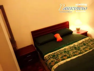 a bed with a green comforter with an orange sock on it at RF Parkview Residence Homestay in Tanah Rata