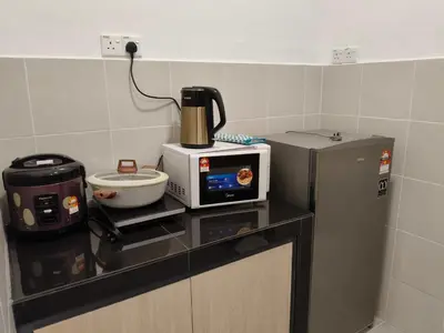 a kitchen counter with a microwave and a refrigerator at Dream studio Emerald avenue in Cameron Highlands