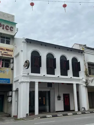 a white building with black windows on a street at Hotel Ban Sheng Teik in Ipoh